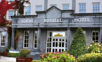 "a hotel entrance with a sign that reads "" slieve russell hotel "" and a flower bed in front" at Slieve Russell Hotel