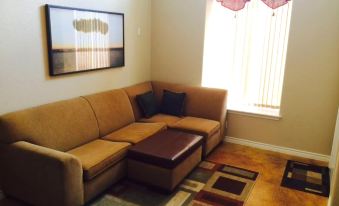 a brown couch with a brown ottoman is placed in front of a window with blinds at Texas Star Lodges