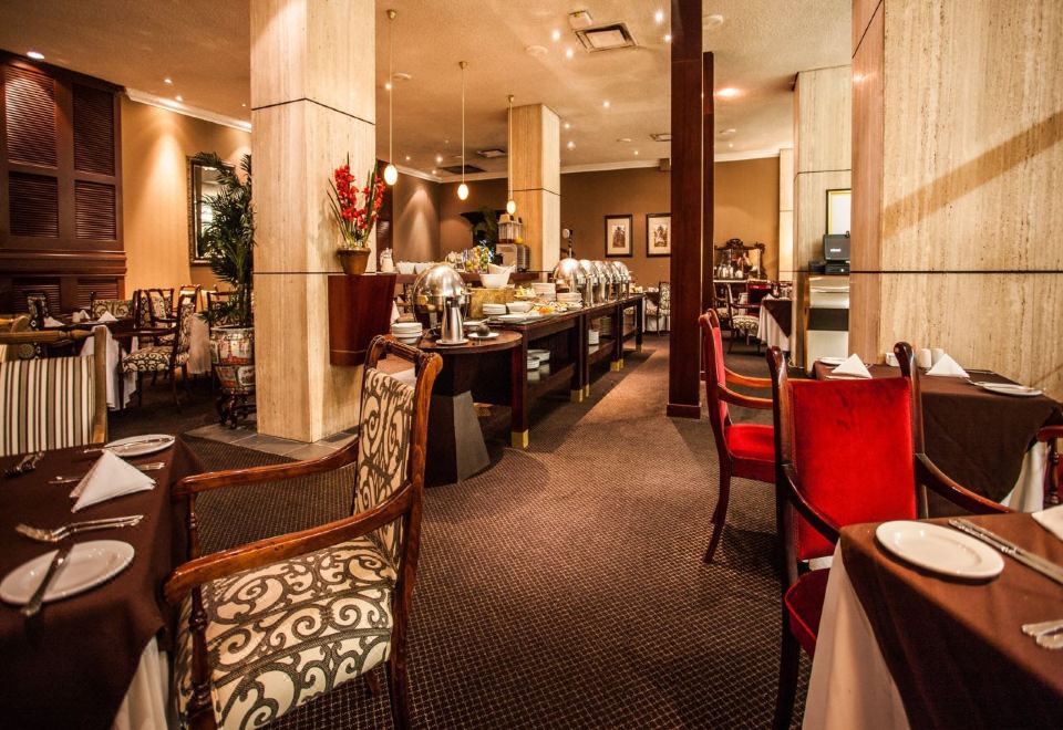 a well - decorated dining room with a buffet table and chairs , as well as other furniture such as couches and tables at The Royal Hotel by Coastlands Hotels & Resorts