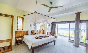 a large bed with a white canopy is in the middle of a room with a view of the ocean at Quynh Vien Resort Ha Tinh