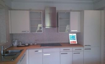 a modern kitchen with white cabinets and a wooden countertop features a microwave oven above the range at The Lansdown