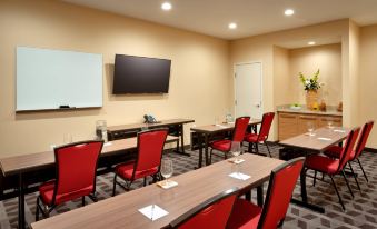 a conference room with red chairs arranged in rows and a tv mounted on the wall at TownePlace Suites Clovis