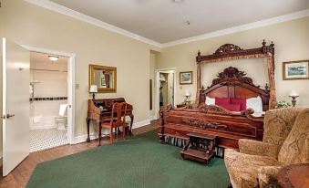 a spacious bedroom with a large wooden bed , a piano , and a bathroom adjacent to it at Lafayette Hotel Marietta