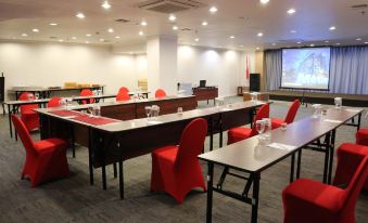 a conference room set up for a meeting , with tables and chairs arranged in rows at Metland Hotel Cirebon by Horison