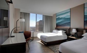 a modern hotel room with a large window offering a view of the city , white beddings , and wooden floors at Winston-Salem Marriott