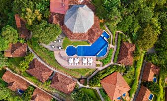 aerial view of a house with a large pool surrounded by greenery and a golf course at Punta Islita, Autograph Collection