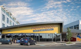 "a blue car is parked in front of a yellow building with the sign "" newmason "" on it" at Mercure Warragul