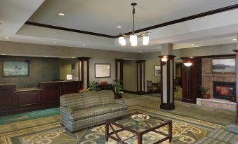 a well - lit hotel lobby with a large couch , tables , and a reception desk in the background at Homewood Suites by Hilton Dover - Rockaway