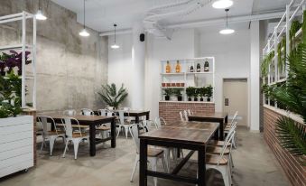 a dining room with several tables and chairs , along with a bookshelf filled with bottles at Rydges Mackay Suites, an EVT hotel