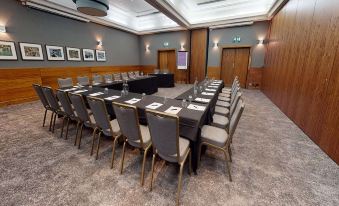 a conference room with a long table , chairs , and various items on the table , including books and papers at Village Hotel Chester St David's