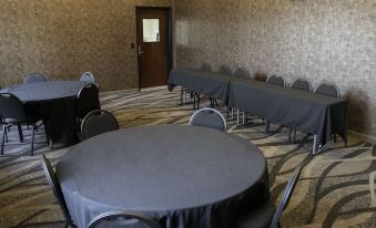 a conference room set up for a meeting , with several round tables and chairs arranged in rows at Cobblestone Hotel & Suites - Two Rivers