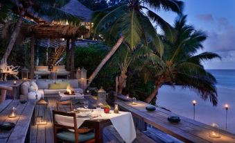 an outdoor dining area with tables and chairs set up on a wooden deck overlooking the ocean at North Island, a Luxury Collection Resort, Seychelles