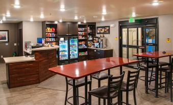 a modern convenience store with a red counter and black chairs , featuring a refrigerated display case at My Place Hotel-Shakopee, MN