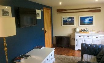 a living room with a blue wall , a flat - screen tv mounted on the wall , and a dining table in the background at The New Inn