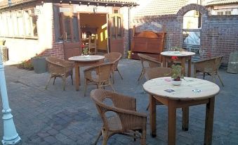 a courtyard with several wooden tables and chairs arranged for outdoor dining , creating a pleasant atmosphere at The Geese and Fountain