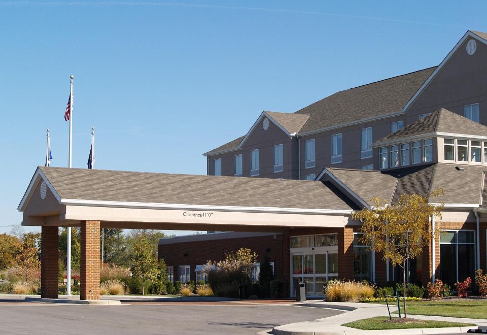 a large hotel with a covered entrance and an american flag on top of it at Hilton Garden Inn Lexington/Georgetown