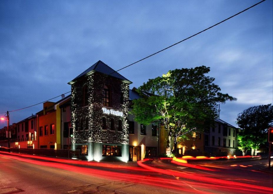 a street scene at night with a brick building and a tree in the foreground at The Twelve Hotel