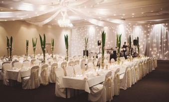a large banquet hall is set up for a wedding reception , with tables covered in white tablecloths and chairs arranged around them at Sage Hotel Wollongong