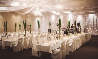 a large banquet hall filled with long tables and chairs , all set up for a formal event at Sage Hotel Wollongong