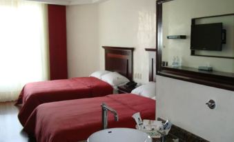 a hotel room with two beds , a sink , and a mirror , all decorated in red and white at Hotel Madeira