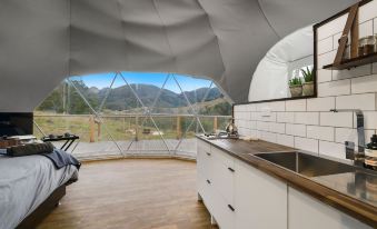 a modern kitchen with a white island and stainless steel sink , next to a large window that overlooks a mountainous landscape at Nature Domes