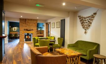 a living room with a brick fireplace , green couches , and chairs arranged in a cozy setting at Woodfalls Inn