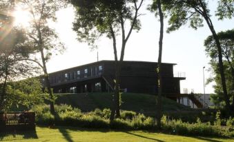 a large wooden building on top of a hill , surrounded by trees and grass , with the sun shining brightly in the background at Okoboji Commons Hotel, Trademark Collection by Wyndham