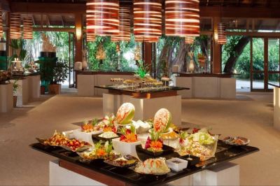 a large dining table filled with a variety of food items , including bowls , plates , and utensils at Vilamendhoo Island Resort & Spa