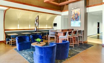 a modern bar area with blue chairs and couches arranged around a coffee table , creating a comfortable seating area at Hyatt Place Pittsburgh Airport/Robinson Mall
