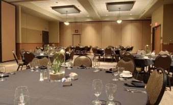 a well - arranged banquet hall with several tables set for a formal event , each table has its own arrangement of white flowers and utensils at King's Pointe Waterpark Resort