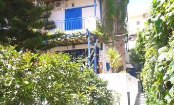 a blue and white apartment building surrounded by trees and bushes , located on a hillside at Amazona