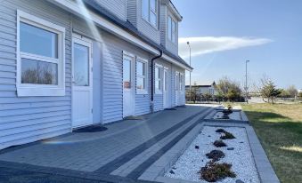 a modern building with a white exterior and blue trim , surrounded by plants and a clear sky at Motel Arctic Wind