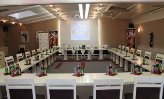 a conference room set up for a meeting , with rows of tables and chairs arranged in a semicircle at Queen's Hotel - Zebra Centre