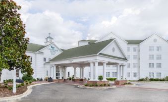 "a large white building with a green roof and a sign that reads "" holiday inn ""." at Homewood Suites by Hilton Olmsted Village (Near Pinehurst, NC)