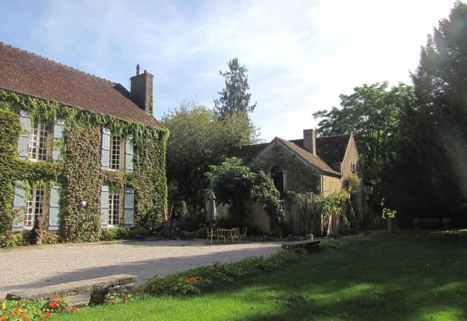 a large house with a driveway and greenery surrounding it , surrounded by trees and grass at Le Petit Paris