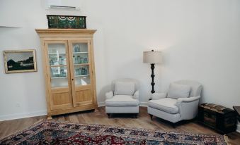 a living room with two white chairs , a rug , and a wooden cabinet on the floor at Briar Barn Inn