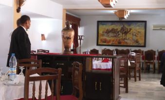 a man in a suit standing behind a counter , possibly in a restaurant or a dining room at Hotel Antar