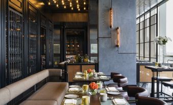 a modern restaurant with wooden tables , chairs , and couches arranged for a group of people to enjoy their meal at Swissôtel Jakarta PIK Avenue