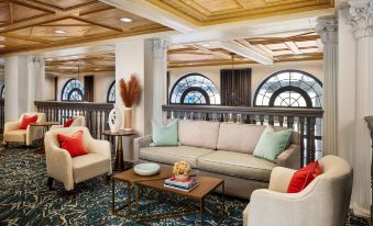 a spacious living room with a couch , two chairs , and a coffee table in the center at The Terrace Hotel Lakeland, Tapestry Collection by Hilton