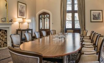 a large wooden conference table with chairs , set in a room with windows and curtains at De Vere Tortworth Court