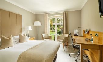 a well - lit hotel room with a bed , desk , chairs , and a window , providing a comfortable living space at Lion Quays Resort