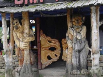 "a wooden doorway with two carved wooden figures on either side , and a sign reading "" dinài "" above the door" at Troll