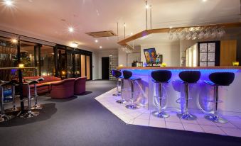 a modern bar with a blue and purple design , black stools , and a chandelier hanging from the ceiling at Springwood Motor Inn