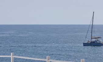 a sailboat is sailing in the ocean , with a person standing on a boat deck observing the view at Notos Therme and Spa