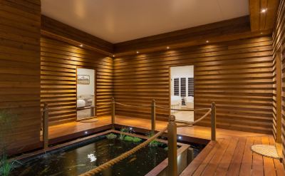 a wooden room with a fish pond in the center , surrounded by benches and railings at The Swan Valley Retreat