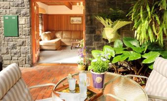 a cozy living room with wooden furniture , including a couch , chairs , and a dining table at Mary Cards Coach House