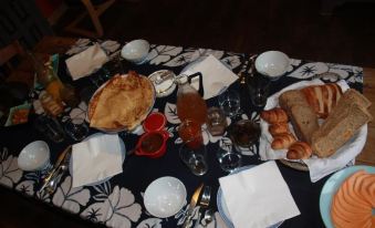 a table is set with a variety of food items , including pastries and drinks , on blue and white tablecloth at La Vieille Ferme