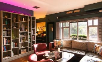 a modern living room with a red couch , black leather chairs , and a bookcase filled with books at The Twelve Hotel