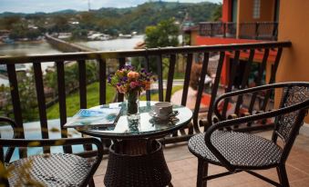 a small table with a vase of flowers sits on a balcony overlooking a body of water at Samprasob Resort
