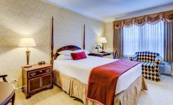 a large bed with a red blanket is in the middle of a room with two nightstands and lamps at Carleton of Oak Park